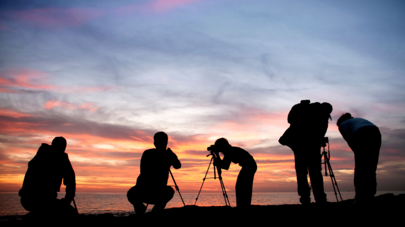Photographers taking a photo of a sunset.